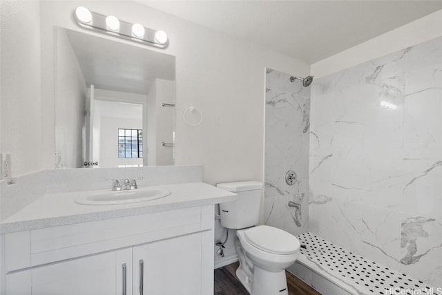 bathroom featuring toilet, hardwood / wood-style floors, vanity, and a tile shower