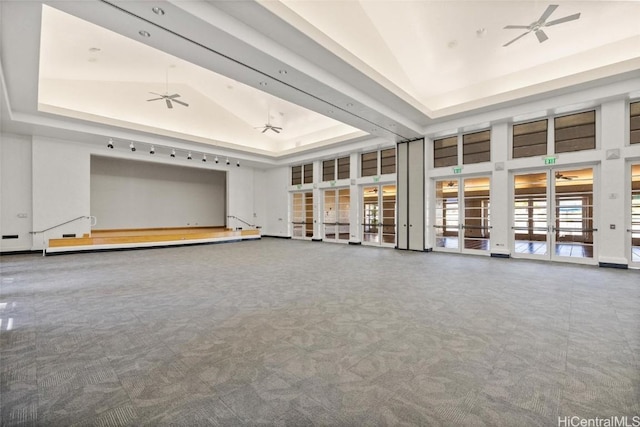 unfurnished living room featuring carpet, french doors, high vaulted ceiling, and a raised ceiling