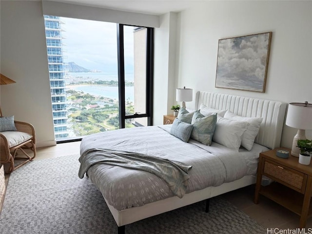 bedroom featuring multiple windows, a water view, and hardwood / wood-style flooring