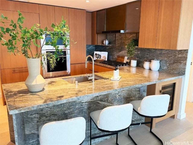 kitchen with sink, decorative backsplash, kitchen peninsula, and appliances with stainless steel finishes