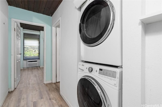 laundry area featuring stacked washer and dryer, light hardwood / wood-style flooring, an AC wall unit, and wood ceiling