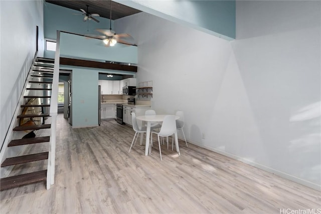 unfurnished dining area featuring a high ceiling, light hardwood / wood-style floors, and ceiling fan