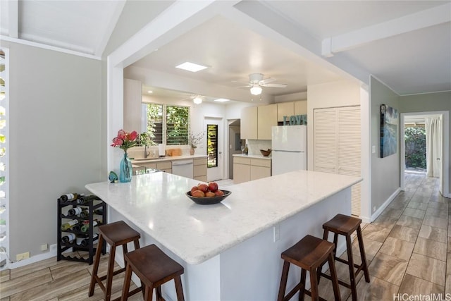 kitchen featuring kitchen peninsula, a kitchen breakfast bar, white appliances, and ceiling fan