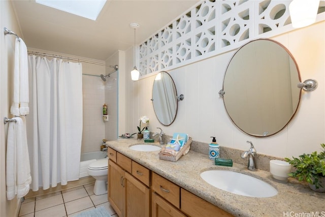 full bathroom featuring a skylight, tile patterned floors, vanity, shower / bath combo with shower curtain, and toilet