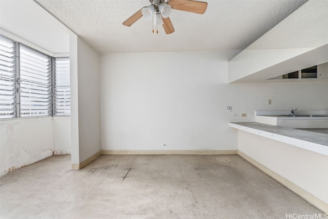 unfurnished room featuring ceiling fan, sink, and a textured ceiling