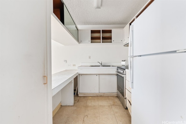 kitchen featuring white refrigerator, white cabinetry, sink, and stainless steel electric range oven