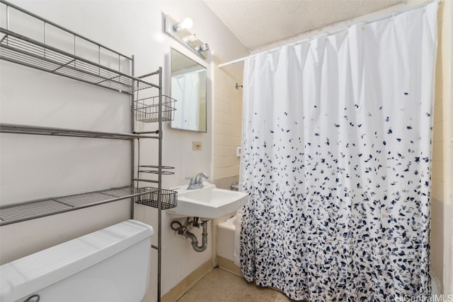 bathroom featuring shower / bath combo with shower curtain, a textured ceiling, and toilet