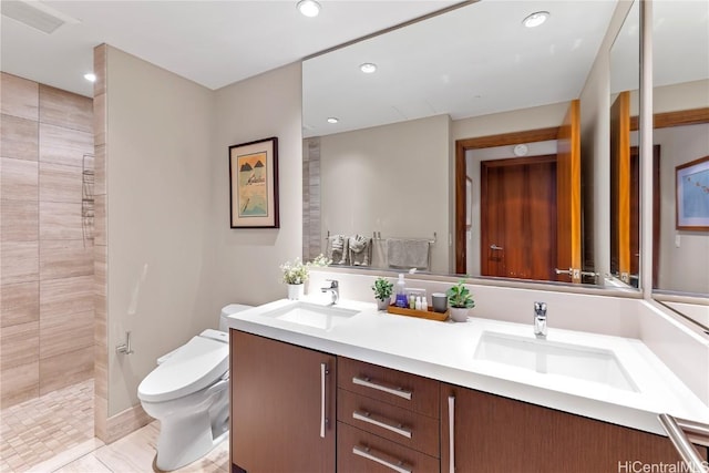 bathroom with tile patterned flooring, vanity, toilet, and a tile shower