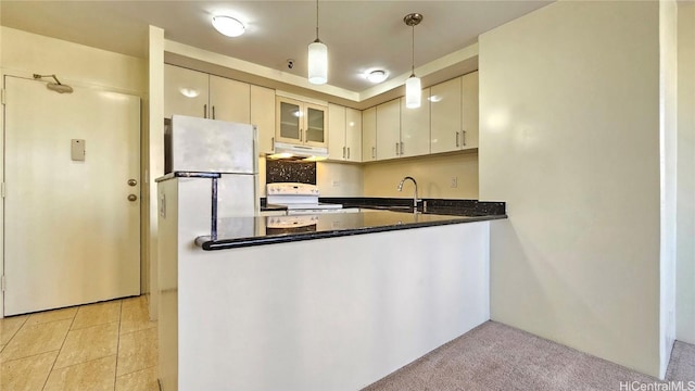 kitchen featuring hanging light fixtures, kitchen peninsula, dark stone countertops, light colored carpet, and white stove