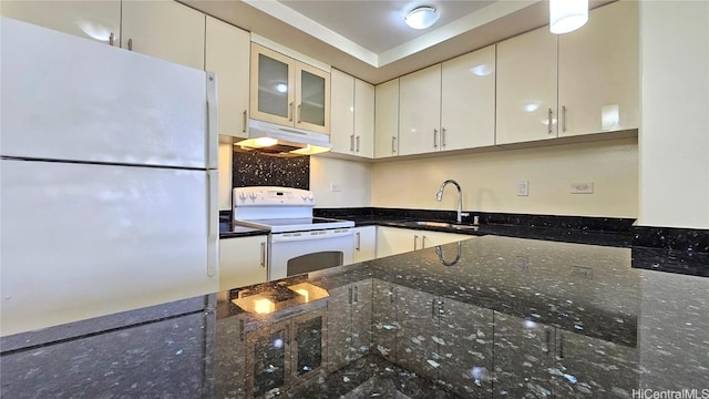 kitchen with backsplash, dark stone counters, white appliances, sink, and white cabinets