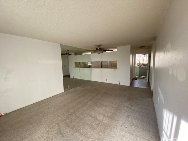 unfurnished room featuring a textured ceiling, ceiling fan, and light carpet