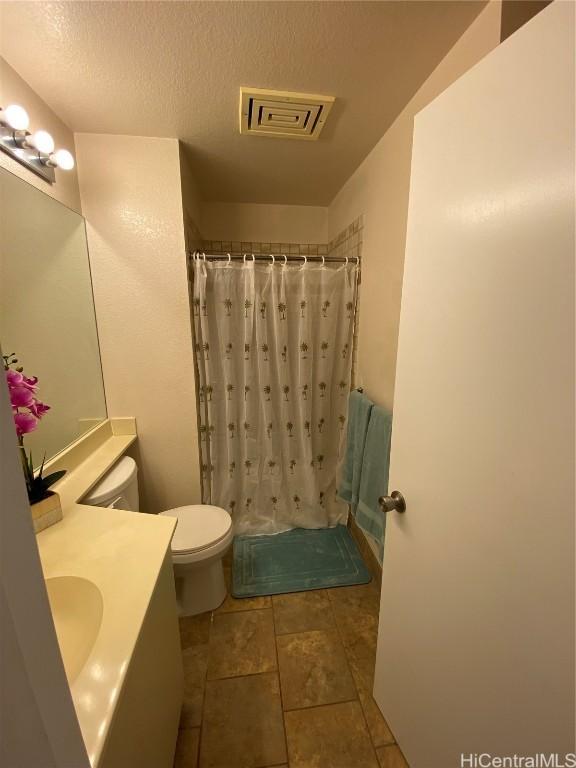 bathroom with vanity, tile patterned floors, a shower with shower curtain, toilet, and a textured ceiling