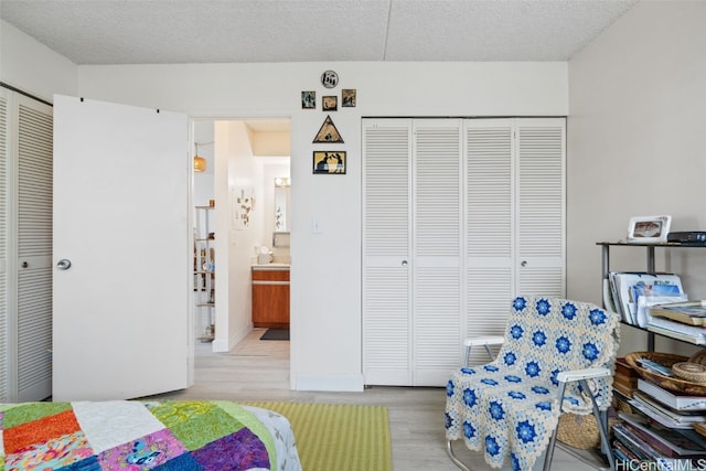 bedroom featuring sink, light wood-type flooring, a textured ceiling, and a closet