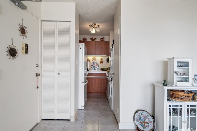 kitchen with white appliances, light tile patterned floors, and a textured ceiling