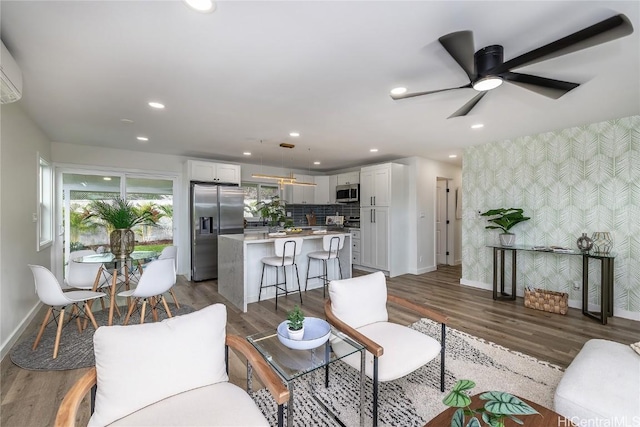 living room featuring a wall mounted AC, ceiling fan, and dark hardwood / wood-style floors