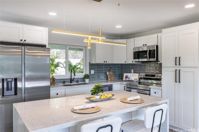 kitchen featuring white cabinets, appliances with stainless steel finishes, pendant lighting, and sink