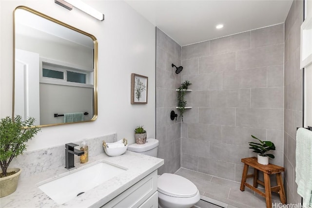 bathroom with tiled shower, tile patterned flooring, vanity, and toilet