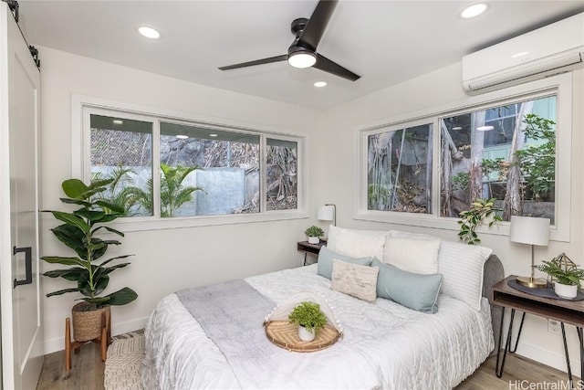 bedroom featuring hardwood / wood-style floors, a wall unit AC, and ceiling fan