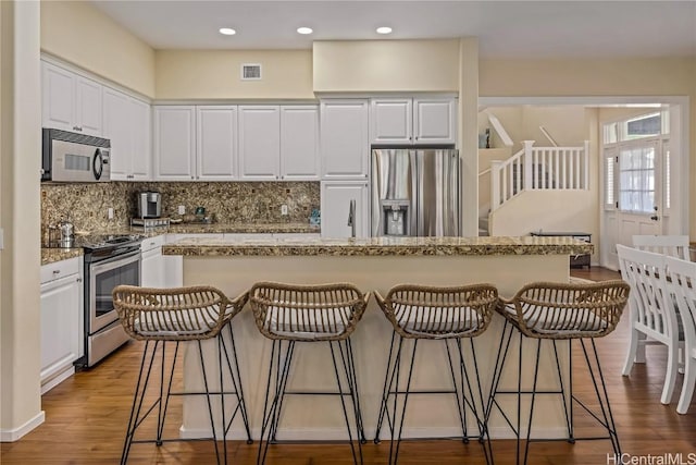 kitchen with white cabinets, a center island, stainless steel appliances, and a breakfast bar