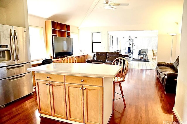 kitchen with stainless steel fridge with ice dispenser, dark hardwood / wood-style floors, a kitchen island, and plenty of natural light