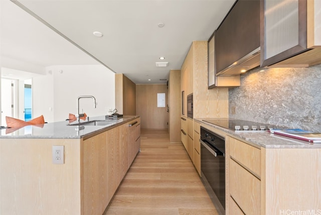 kitchen with light wood-type flooring, light brown cabinets, sink, and black appliances