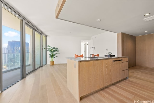 kitchen featuring light brown cabinets, a center island with sink, light hardwood / wood-style flooring, and sink