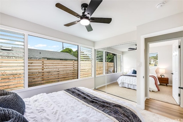 bedroom with ceiling fan, light wood-type flooring, multiple windows, and a closet