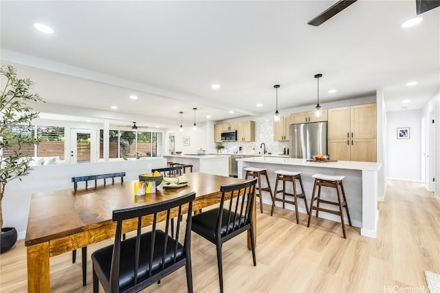 dining space featuring ceiling fan, light wood-type flooring, and sink