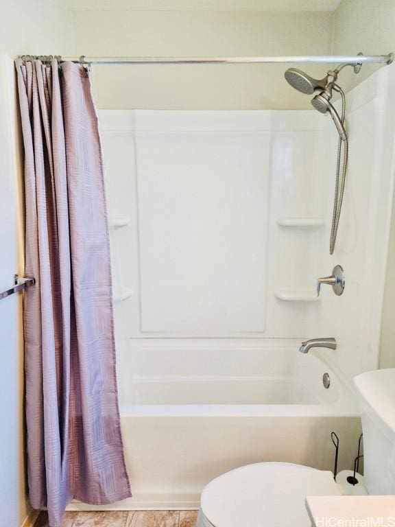 bathroom featuring tile patterned floors, toilet, and shower / bath combo with shower curtain