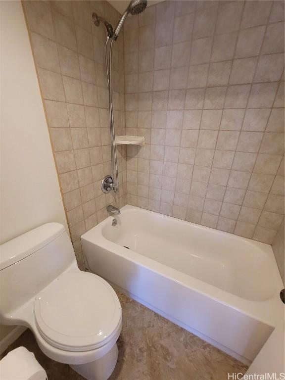 bathroom featuring tiled shower / bath combo and toilet