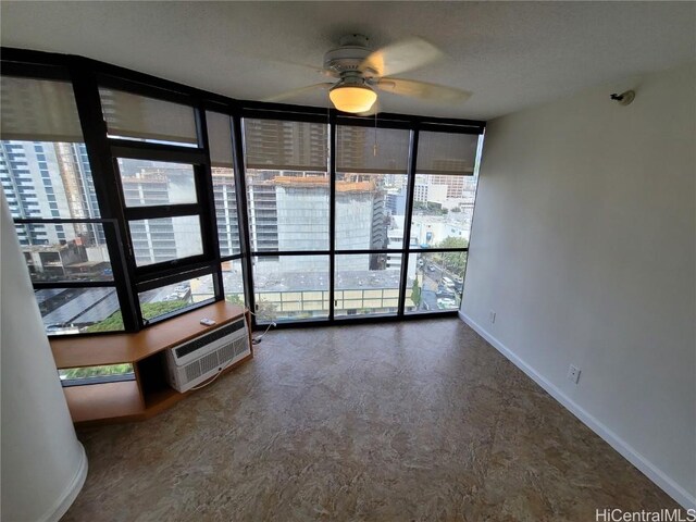 unfurnished sunroom with a wall mounted air conditioner, plenty of natural light, and ceiling fan