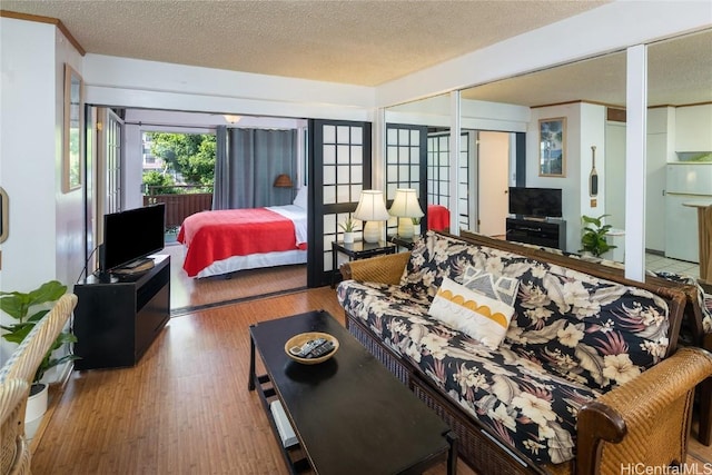 bedroom with french doors, hardwood / wood-style flooring, a textured ceiling, white fridge, and a closet