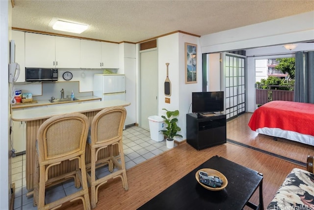 kitchen with white cabinets, a kitchen bar, light wood-type flooring, and sink