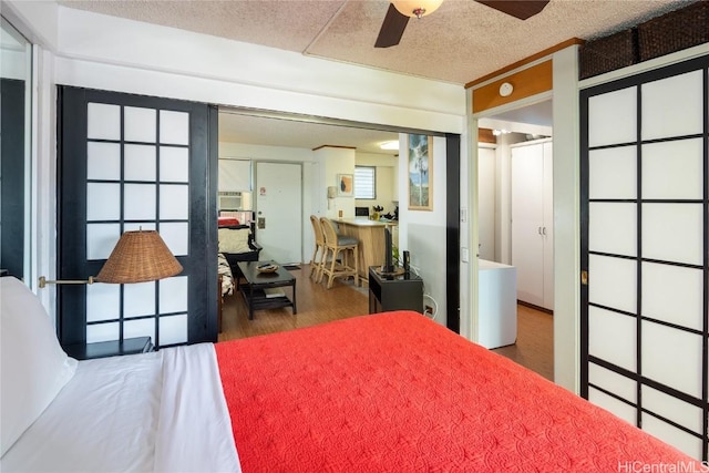 bedroom with a textured ceiling, dark hardwood / wood-style floors, and ceiling fan