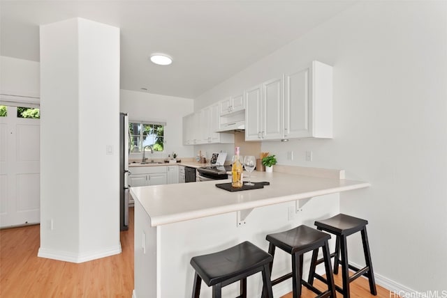 kitchen featuring sink, kitchen peninsula, light hardwood / wood-style floors, white cabinetry, and stainless steel appliances