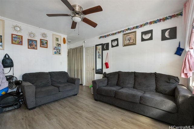 living room with ceiling fan, wooden walls, and light hardwood / wood-style floors