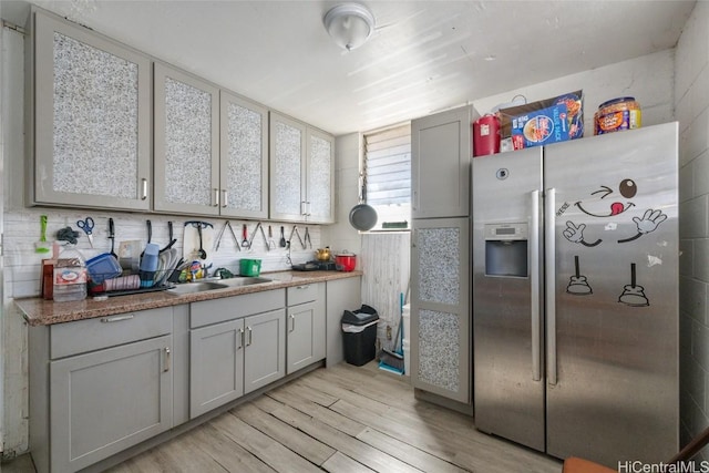 kitchen featuring gray cabinetry, stainless steel fridge with ice dispenser, light hardwood / wood-style flooring, and sink