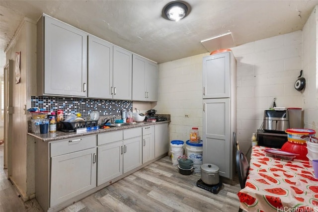 kitchen featuring white cabinets, light wood-type flooring, dark stone countertops, and sink