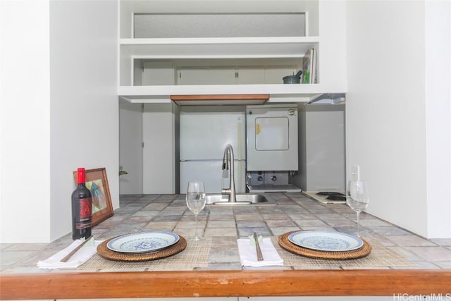 interior space featuring built in shelves, white refrigerator, sink, and stacked washer / dryer