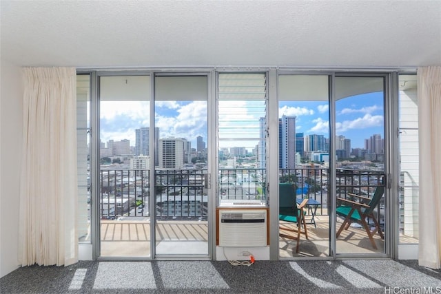 unfurnished room featuring a wall mounted air conditioner, carpet floors, a textured ceiling, and a wall of windows