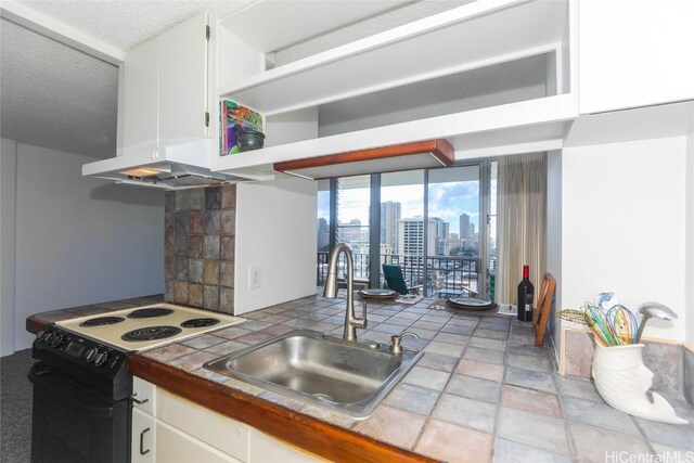 kitchen featuring tile countertops, white cabinets, white electric range, and sink