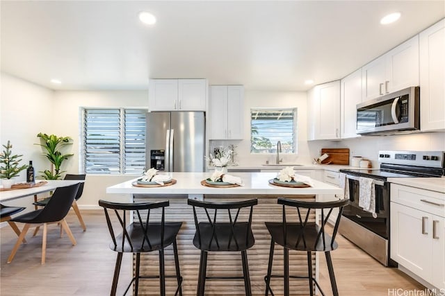 kitchen featuring a breakfast bar, white cabinets, light hardwood / wood-style floors, and appliances with stainless steel finishes