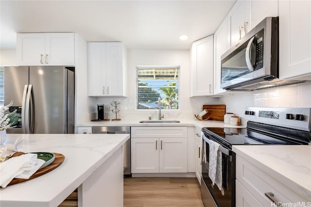 kitchen featuring white cabinetry, sink, stainless steel appliances, and light wood-type flooring