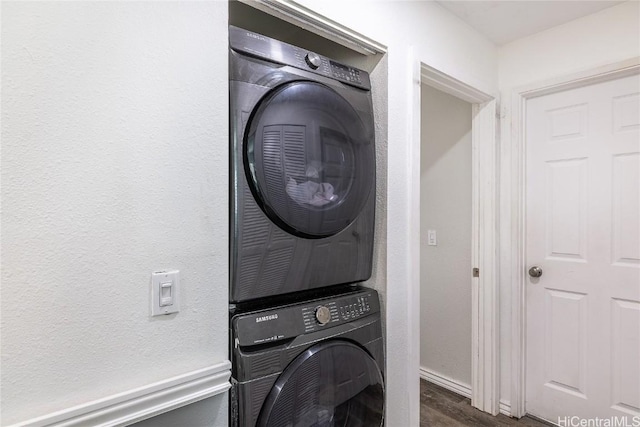 washroom with stacked washer / dryer and dark wood-type flooring