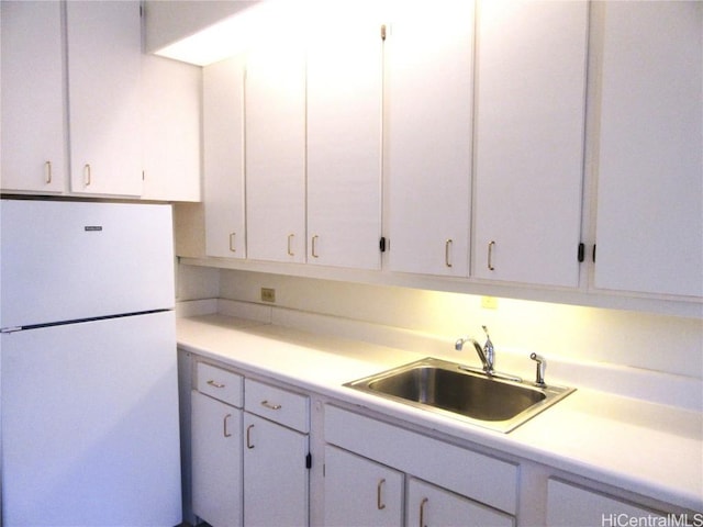 kitchen with white cabinets, white fridge, and sink