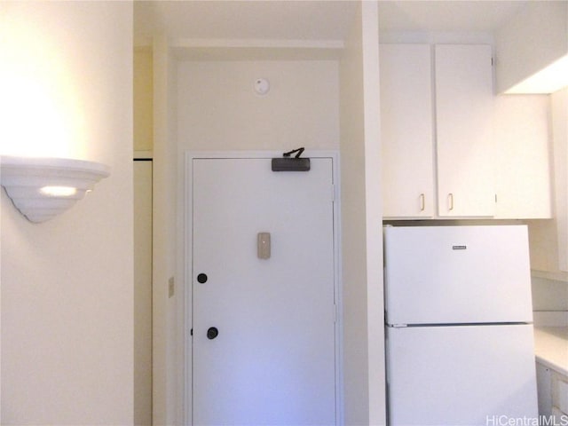 interior space with white refrigerator and white cabinetry