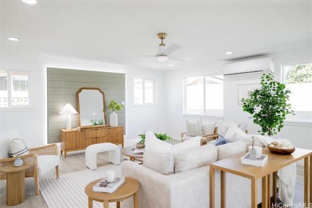 living room featuring plenty of natural light, ceiling fan, a wall unit AC, and light hardwood / wood-style flooring