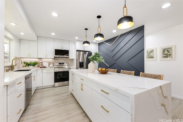 kitchen featuring a center island, white cabinetry, hanging light fixtures, and appliances with stainless steel finishes