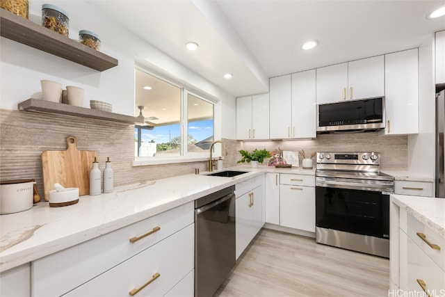 kitchen featuring backsplash, sink, light stone countertops, appliances with stainless steel finishes, and white cabinetry