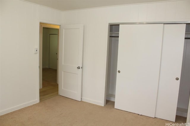 unfurnished bedroom featuring light carpet, a closet, and ornamental molding